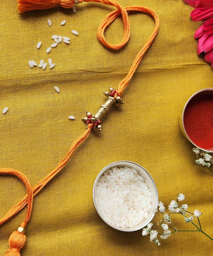 Handmade dhokra rakhi with yellow mercerised cotton thread