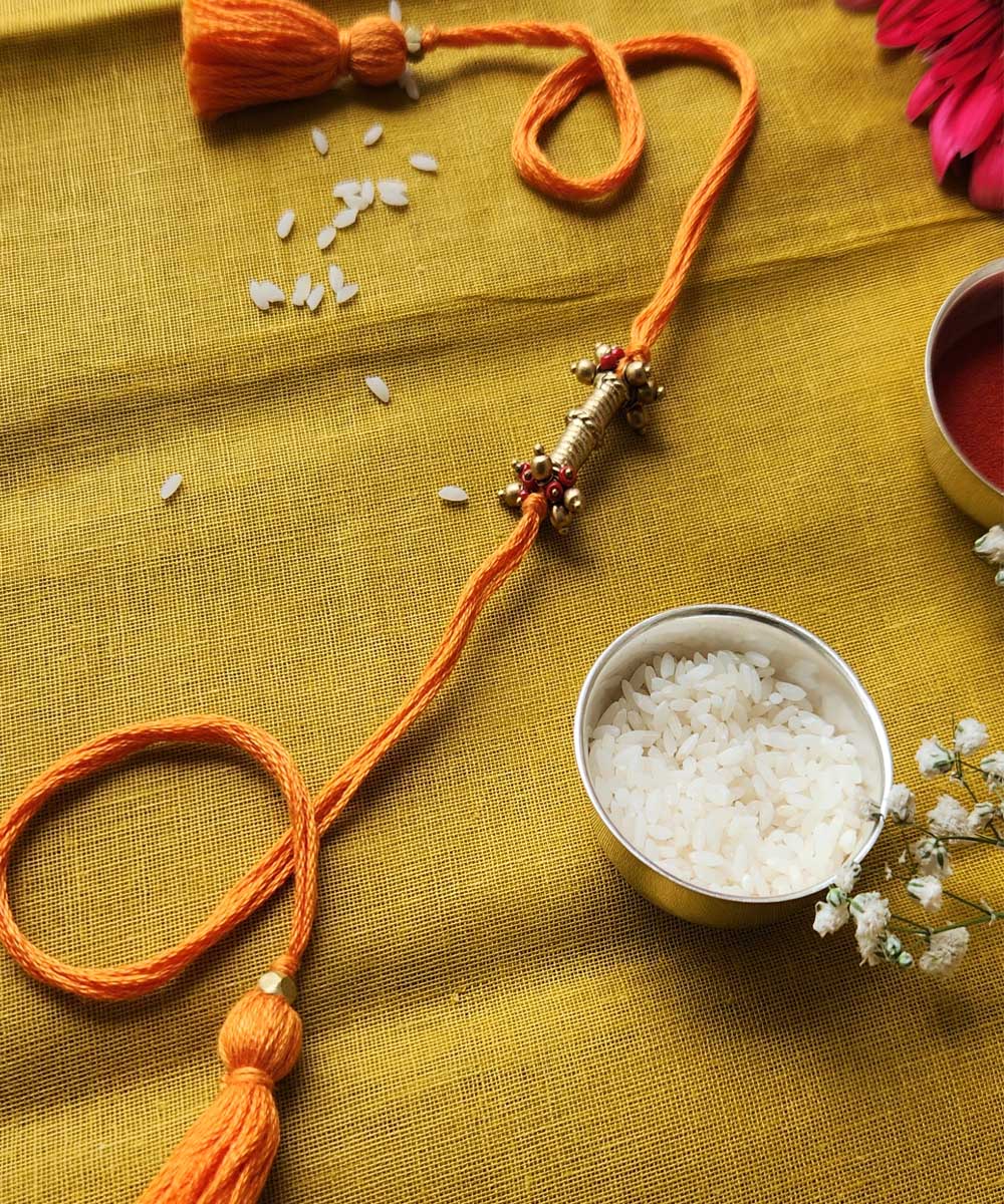 Handmade dhokra rakhi with yellow mercerised cotton thread