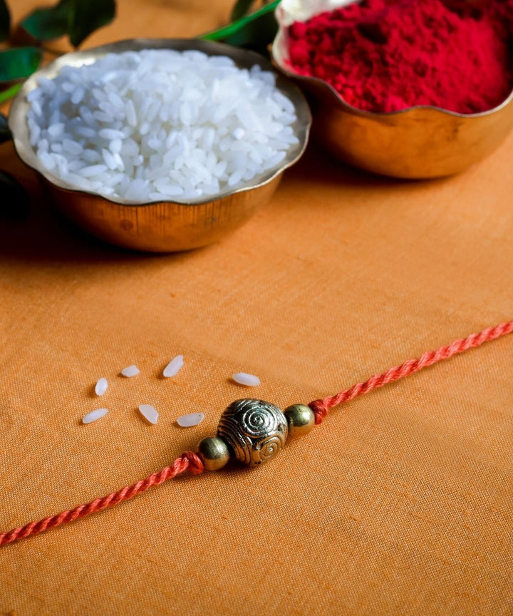 Handcrafted dhokra rakhi with red mercerised cotton thread
