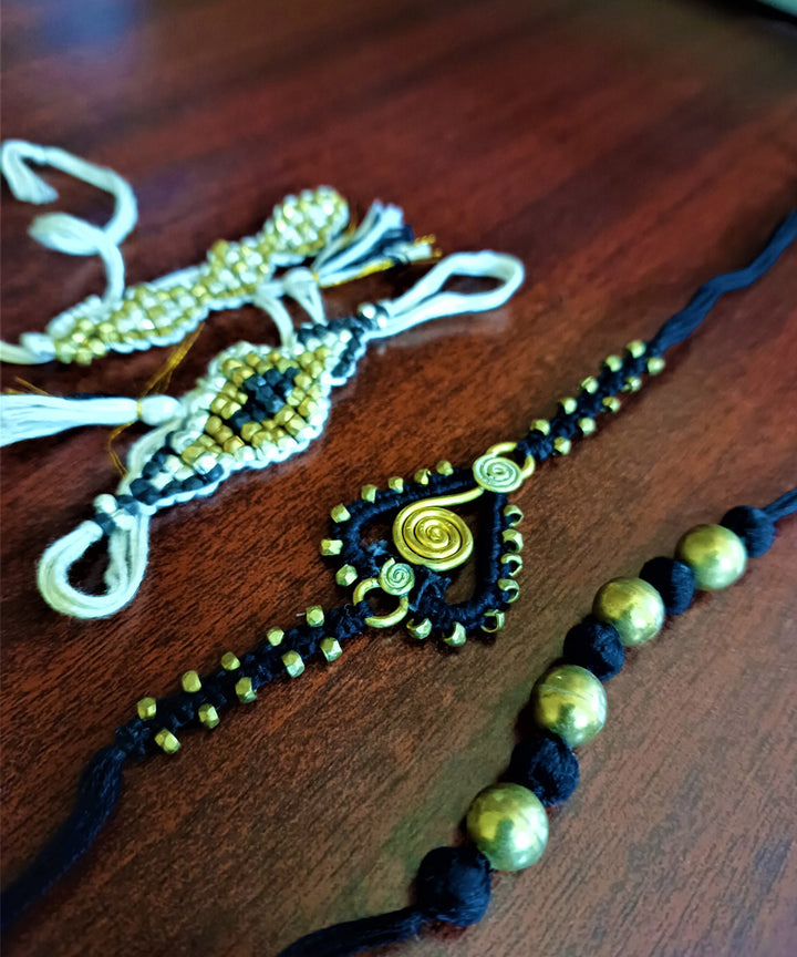 Handcrafted set of four dhokra brass rakhi with cotton thread
