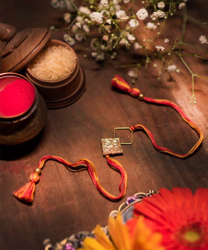 Handcrafted dokhra rakhi with orange mercerised cotton thread