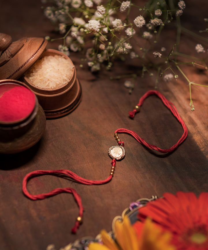 Handcrafted dhokra rakhi with red mercerised cotton thread