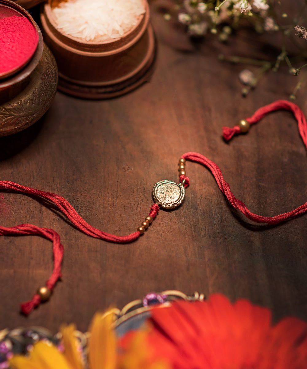 Handcrafted dhokra rakhi with red mercerised cotton thread