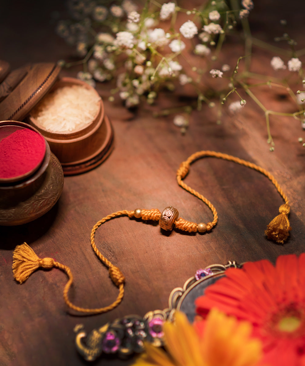 Hand crafted dokhra rakhi with yellow mercerised cotton thread