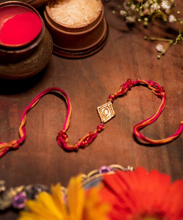 Handcrafted dhokra rakhi with pink mercerised cotton thread