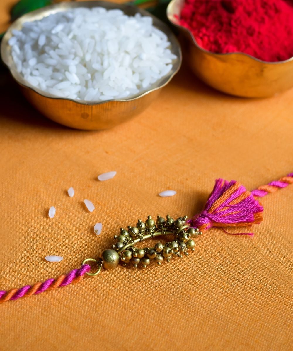 Handcrafted brass rakhi with pink orange mercerised cotton thread