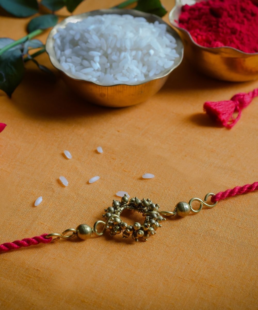 Handcrafted brass rakhi with red mercerised cotton thread