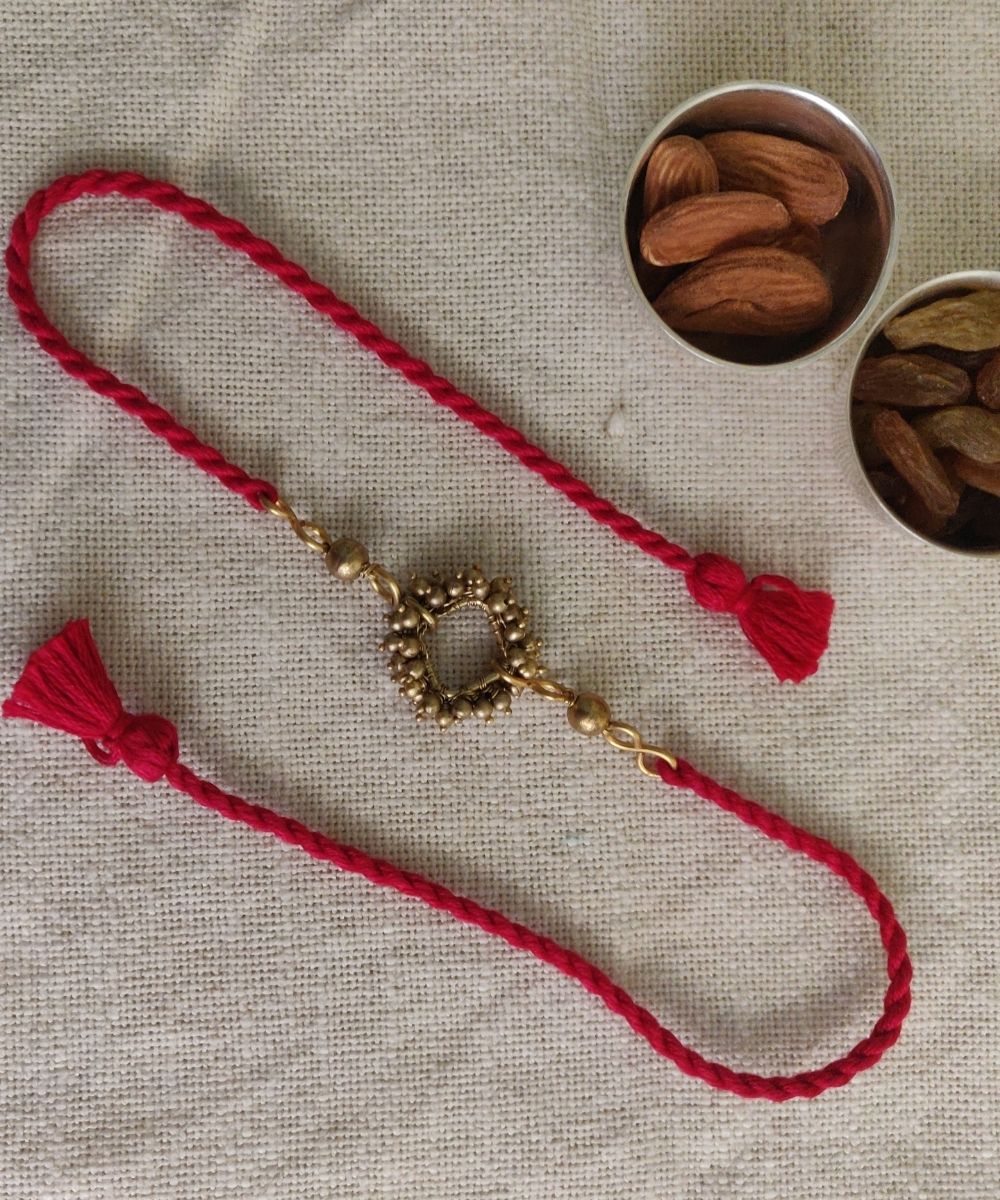 Handcrafted brass rakhi with red mercerised cotton thread
