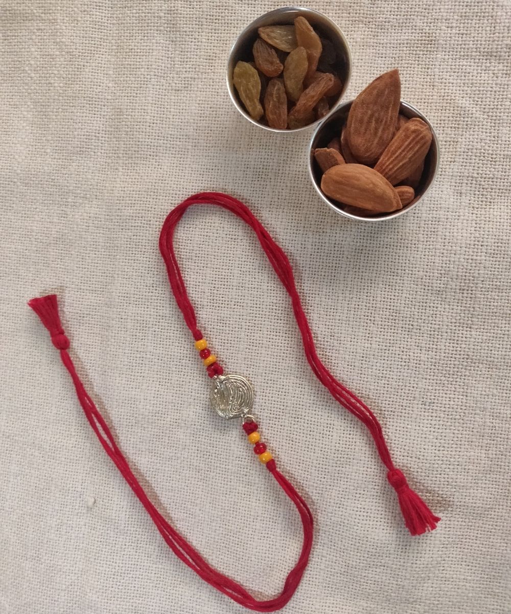 Hand crafted dhokra rakhi with red mercerised cotton thread