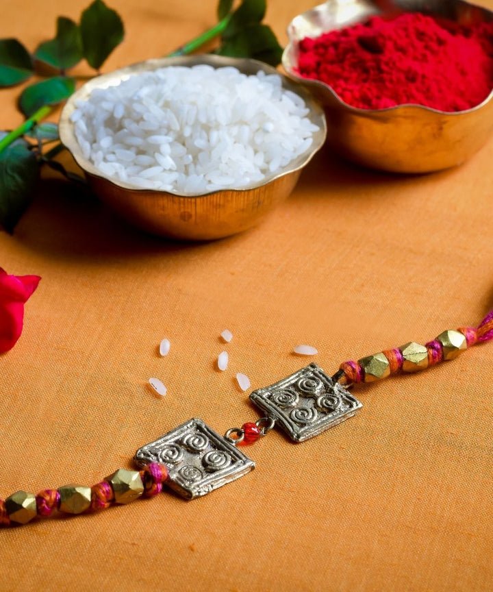 Handcrafted dhokra rakhi with red mercerised cotton thread