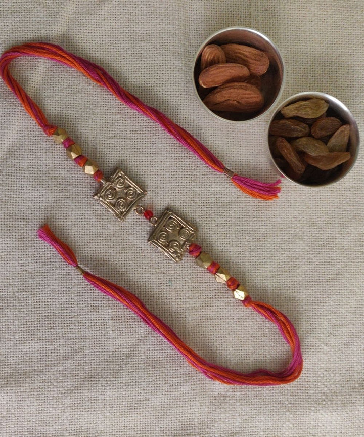 Handcrafted dhokra rakhi with red mercerised cotton thread