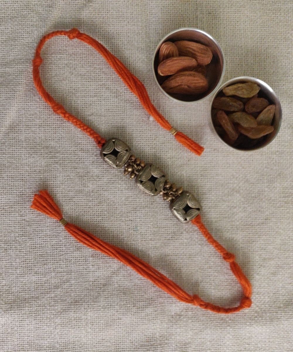 Hand crafted dhokra rakhi with orange mercerised cotton thread
